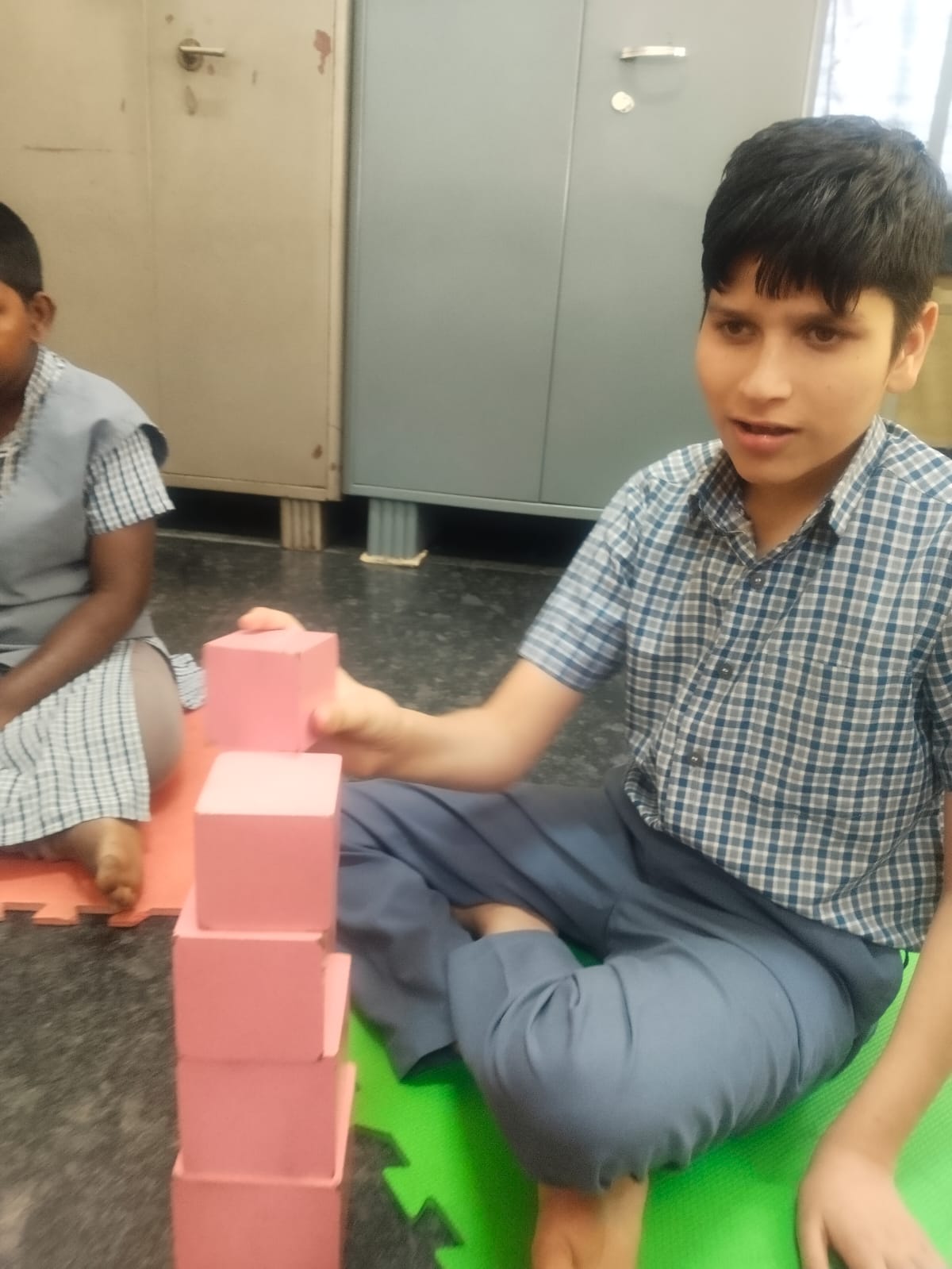 Student stacking pink blocks during a classroom activity